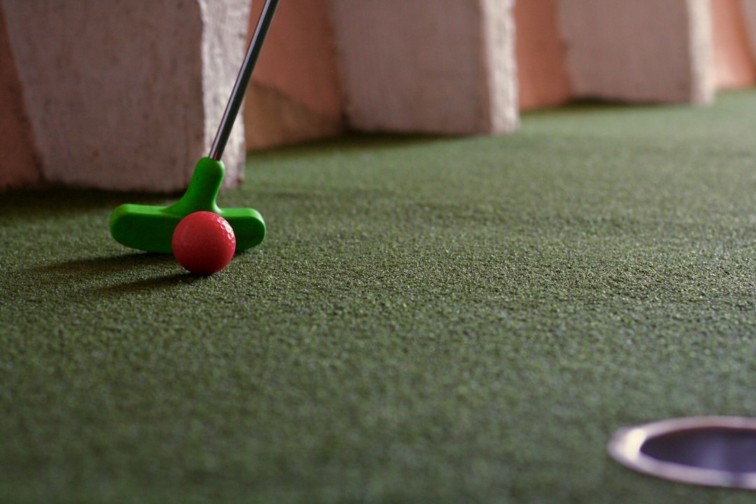 Mini golf putter and red ball on a green putting course